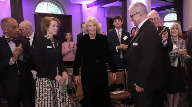 Queen is welcomed to event in Westminster. She is dressed in dark clothing