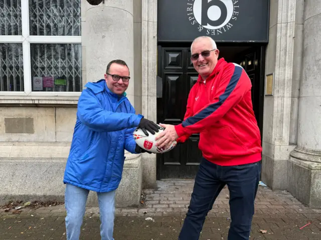 Two people holding the match ball