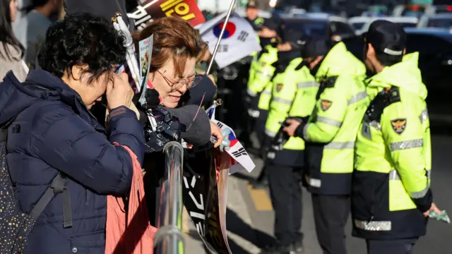 Two women cry next to railing