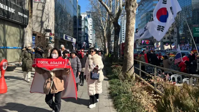 Supporters of South Korea's impeached former president Yoon hold banners outside the court