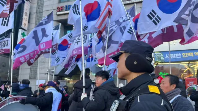 Young men marching down a road holding South Korean flags