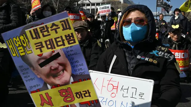 Woman at a protest holding a placard with an image of former South Korean president Yoon Suk Yeol