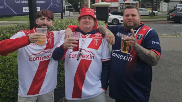 Harry, Darren and Daniel pictured wearing replica kits, each holding up a pint.