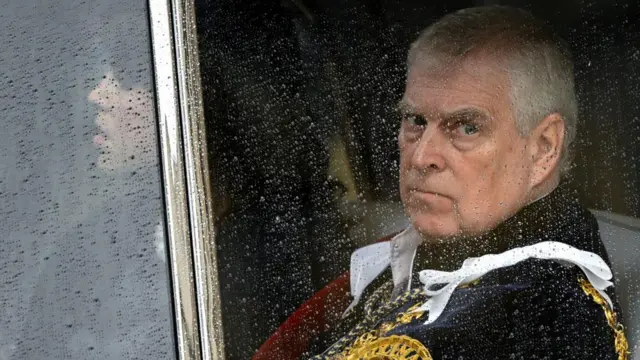Andrew in a car, seen through the window which has rain drops on it.