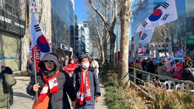 Women marching on a road while holding South Korean flags