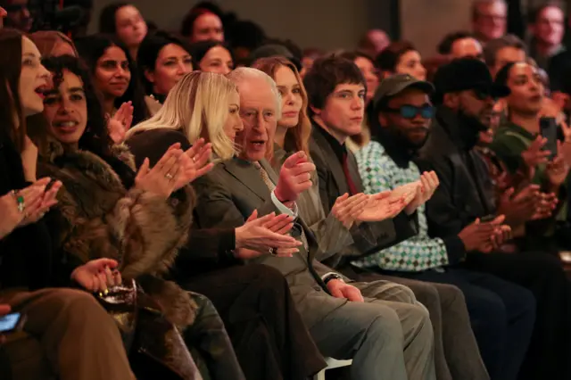 Britain's King Charles and fashion designer Stella McCartney sit on the front row at a fashion show.