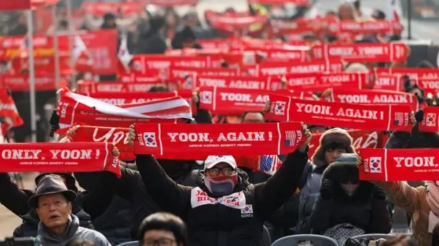 Yoon supporters raising red banners that read "Yoon, Again"
