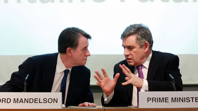 Peter Mandelson and Gordon Brown sit next to each other with placards with their names in front of them.