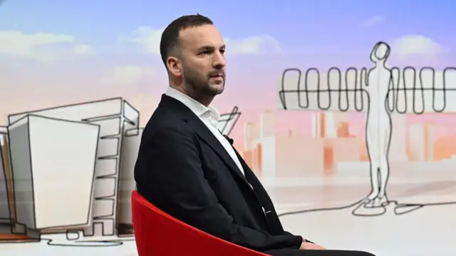 Green Party leader Zack Polanski sits in a read chair