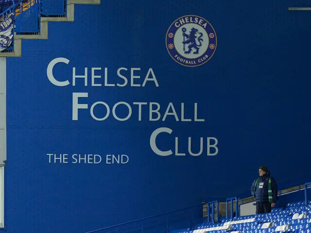 A fan stands next to the Shed End wall at Stamford Bridge