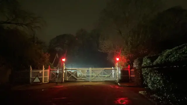 The gates of Royal Lodge with red lights lit at night time