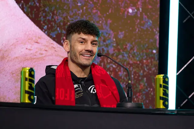 Leigh Wood has a red Nottingham Forest scarf around his neck and is speaking into a microphone as he sits at a table