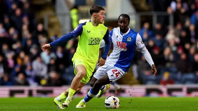 Preston North End's Alfie Devine runs with the ball under pressure from Blackburn Rovers' Moussa Baradji
