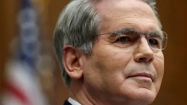 US Treasury Secretary Scott Bessent wearing no-rim glasses and looking to the right of the frame