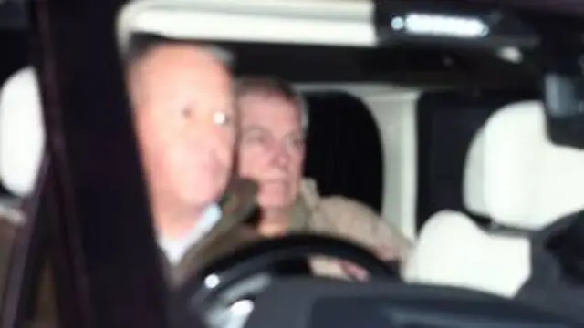 A blurred photograph of Andrew in the back seat of a car