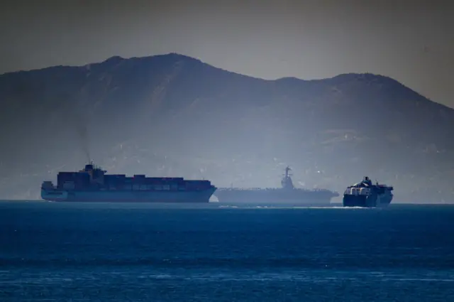 USS Gerald R Ford seen in the background of this picture with the mountains of Morocco behind