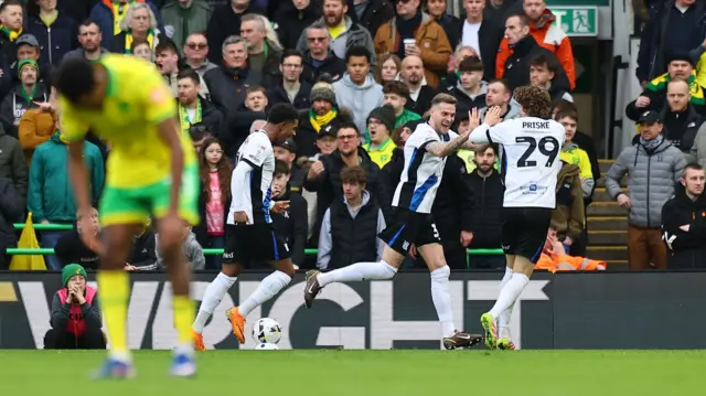Marvin Ducksch runs and claps hands with August Priske (right) as a Norwich player in the foreground bends over in dismay