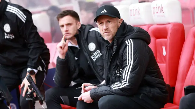 Gary Rowett looks on while sitting in the dugout holding a pen and paper in his hands