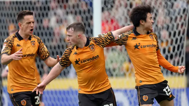 Hull City's Joe Gelhardt holds his left arm around team-mate Yu Hirakawa who clenches his left fist, Amir Hadžiahmetović runs behind