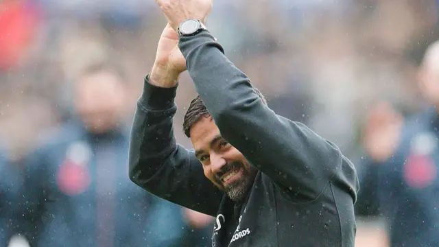 Vitor Matos smiles and holds his hands above his head to clap at full-time