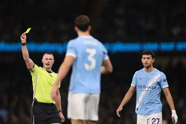 English referee Sam Barrott shows a yellow card to Manchester City's Portuguese defender #03 Ruben Dias