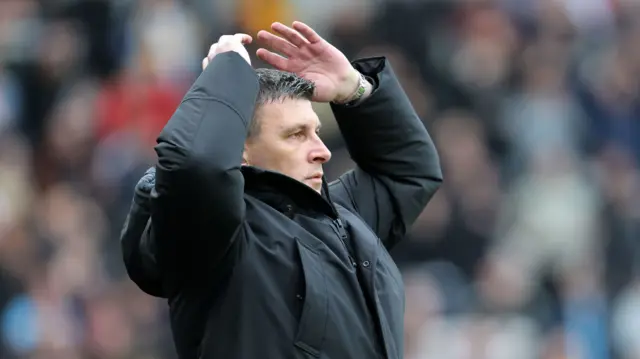 Sergej Jakirovic holds both his arms and hands above his head while watching on the touchline