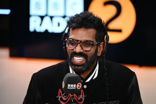 Romesh Ranganathan in front of a BBC Radio 2 microphone