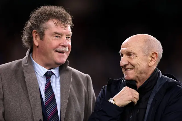Dennis Tueart and Kenny Clements talk prior to the Premier League match between Manchester City and Newcastle United at Etihad Stadium on February 21, 2026 in Manchester, England. (