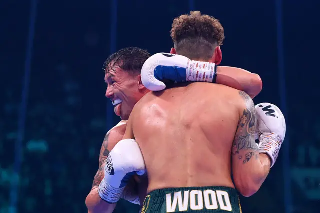 Josh Warrington holds out his tongue and smiles as he hugs Leigh Wood