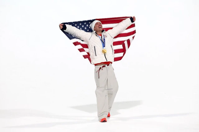 Athlete celebrates winning gold by holding the US flag
