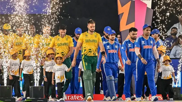 Players from South Africa (L) and India arrive for their national anthems before the start