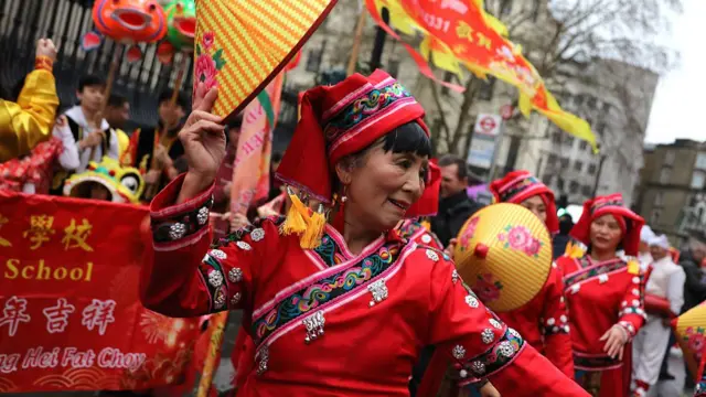 Woman in traditional dress dances among crowd gathered in London to celebrate Chinese New Year