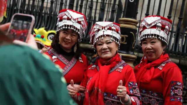 Three women in traditional dress smile as they have their photo taken during Chinese New Year celebrations