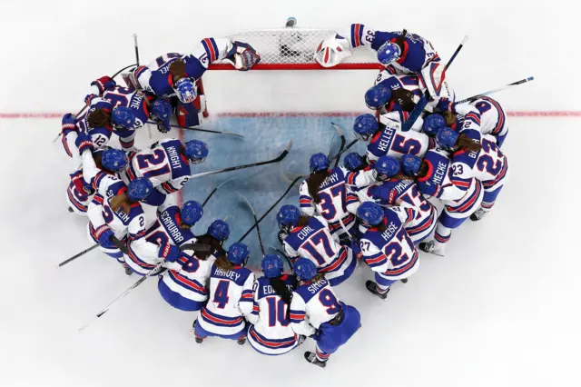 An overhead shot of the US ice hockey team in a huddle