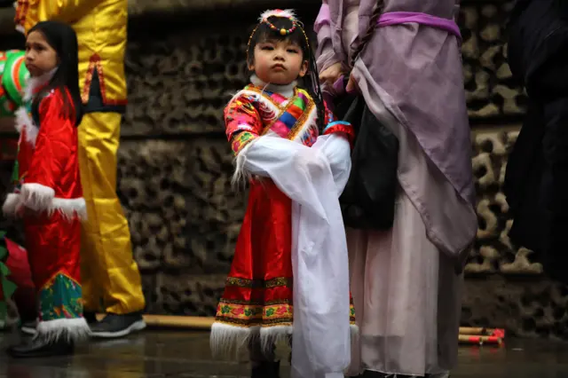 Girl in traditional dress poses at Chinese New Year parade