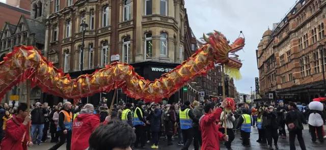 A dragon puppet is paraded through a crowd in central London