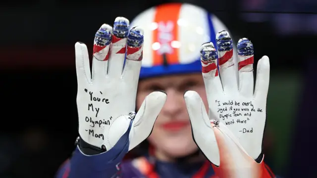 Athlete holds up her gloved hands to the camera displaying personal messages from her parents