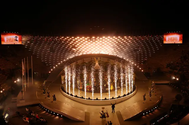 A general view of fireworks and an illuminated chandelier as performers dance during the Milano Cortina 2026 Winter Olympics Closing Ceremony