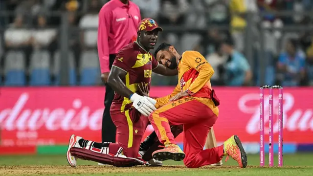 West Indies' Rovman Powell (C) checks Zimbabwe's captain Sikandar Raza