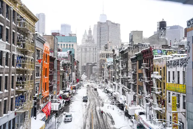 A New York Street blanketed in snow with the skyscrapers of Lower Manhattan in the background
