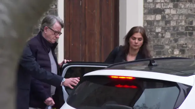 Mandelson and a woman enter an unmarked car as he is arrested