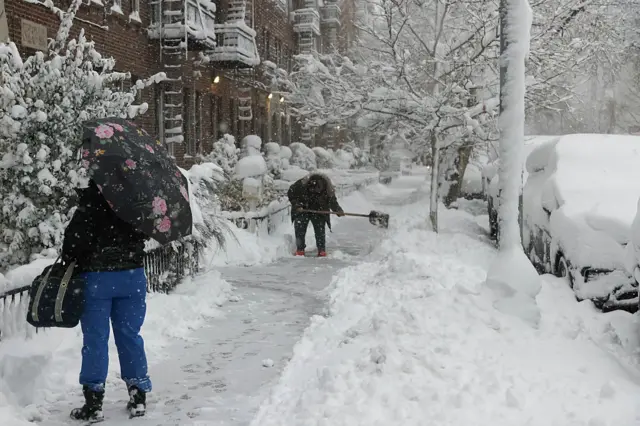 A person shovels snow during a winter storm in the Brooklyn borough of New York on 23 February 2026