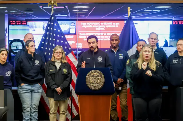 New York Mayor Zohran Mamdani speaks from behind a lectern surrounded by officials