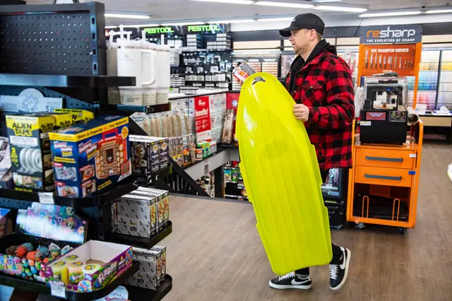 A man carries a snow sled at a hardware store ahead of a winter storm in Quincy, Massachusetts on February 22, 2026.