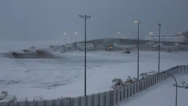 Snow plows clear snow from the tarmac during a winter storm at LaGuardia Airport