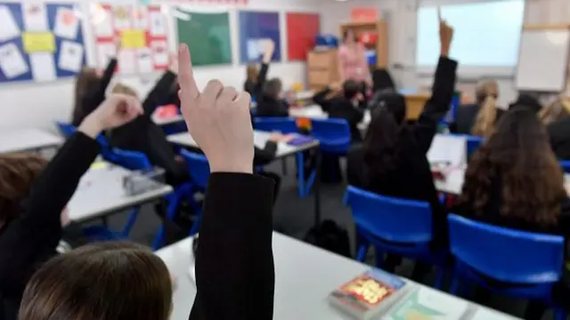 Children raise their hands in a classroom