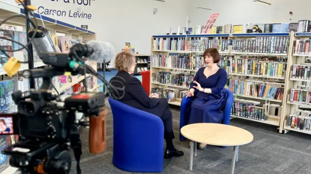 Education Secretary Bridget Phillipson sitting opposite BBC's Branwen Jeffreys on blue chairs in a school library.
