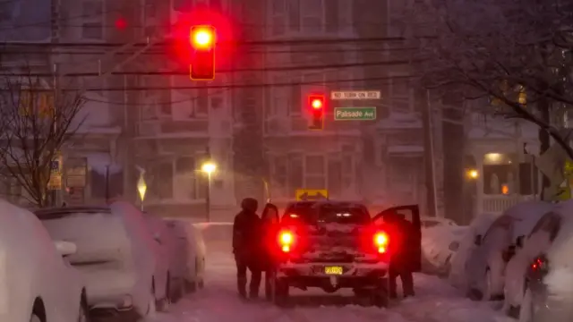 Cars parked along a street are covered in snow