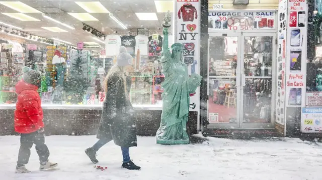 A woman walks by a souvenir store in a blizzard in New York