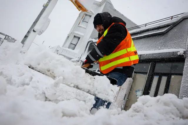 An MTA worker clears snow outside a subway station in New York City during a powerful winter storm, 23 February 2026